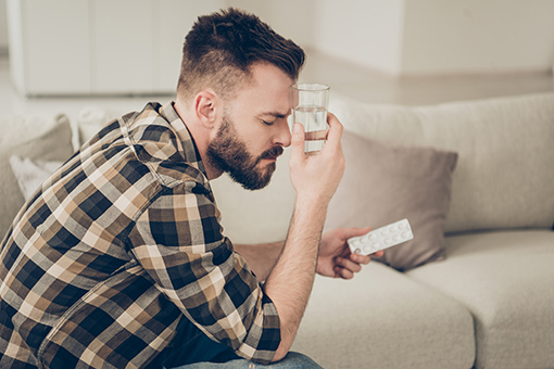 Man Drinking Medicine Contemplating Going To Motorcycle Accident Chiropractor in Phoenix AZ