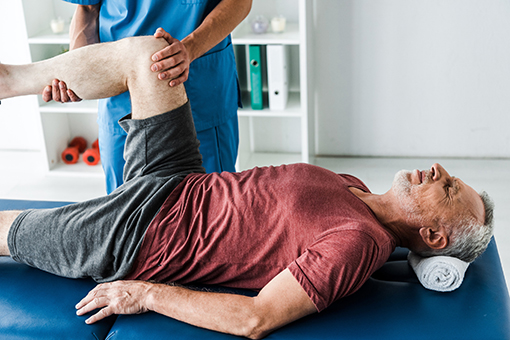 Licensed Chiropractor Holding Leg and Knee of Maryvale AZ Man Suffering From Knee Injury